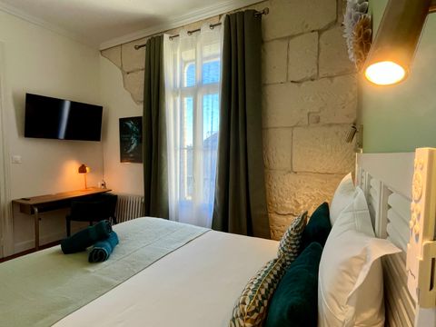 Intérieur d'une chambre, baignée de lumière, un lit double et des décorations murales en papier