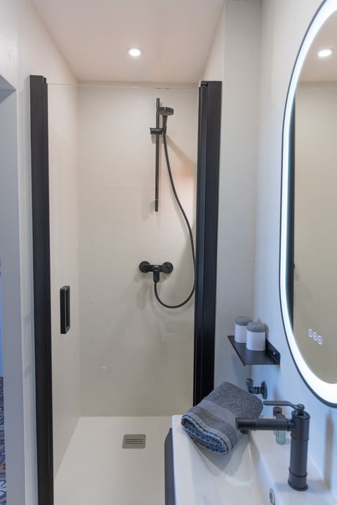 Intérieur d'une salle de bain avec une douche, un lavabo et un mirroir avec éclairage