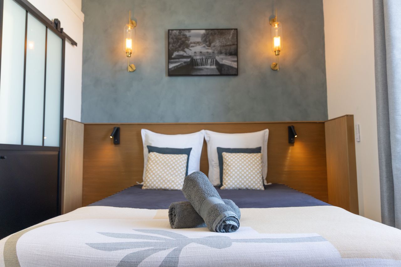 Intérieur d'une chambre aux murs beige et taupe, au sol un carrelage ancien aux motifs fleuris