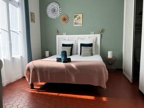 Intérieur d'une chambre, baignée de lumière, un lit double et des décorations murales en papier